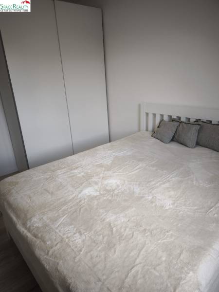 Spálňa v 2-izbovom byte s bielou skriňou a posteľou s vankúšmi.