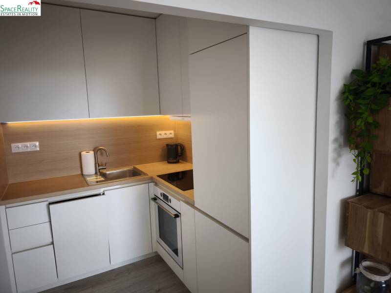 Kuchyňa v 2-izbovom byte so svetlými skrinkami a podlahou s dreveným dekorom.