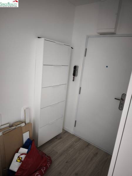 Vstupná predsieň s bielym nábytkom a podlaha s dreveným dekorom v 2-izbovom byte.